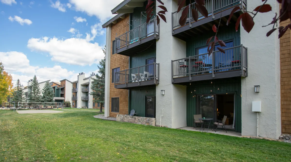 An exterior view of balconies with comfortable chairs overlooking green grass and mature trees. The inviting balconies provide a peaceful space for enjoying the outdoors, whether sipping morning coffee or sharing a glass of wine at sunset.